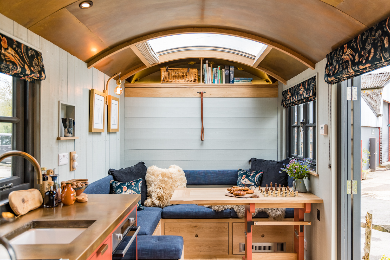 Interior of a handcrafted Blackdown shepherd hut with bespoke kitchen, seating and dining area